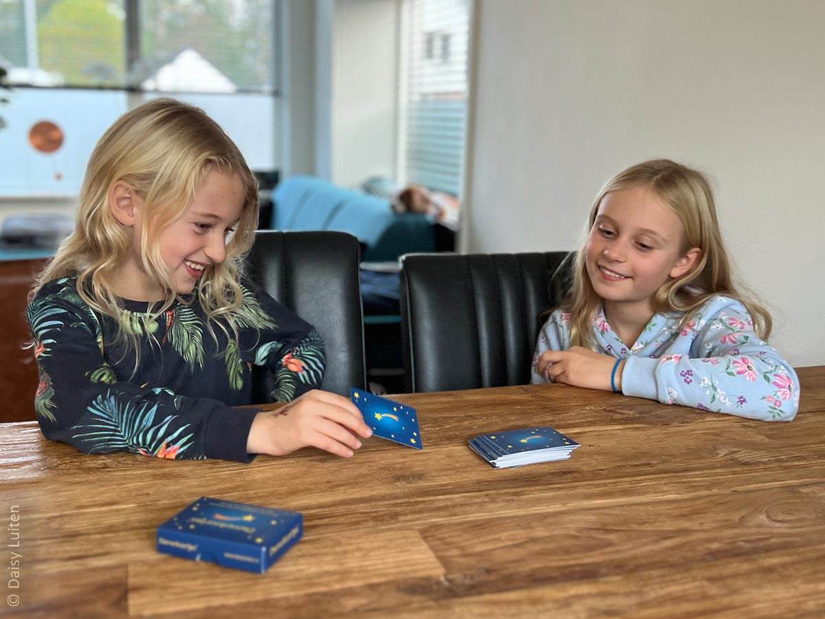 Sterrenkaartjes worden gespeeld door twee kinderen. Eén kind draait enthousiast een blauw vragenkaartje om terwijl de ander geïnteresseerd afwacht. Sterrenkaartjes hebben tot doel herinneringen op te halen na het overlijden van een dierbare.